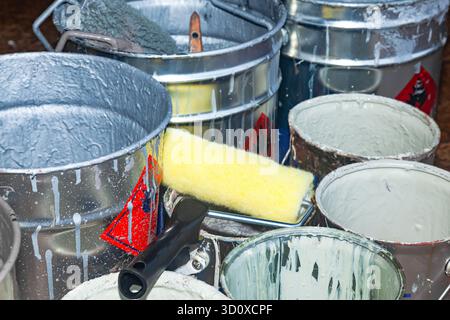 Empty paint buckets containing used rollers and brushes. Stock Photo