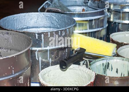 Empty paint buckets containing used rollers and brushes. Stock Photo