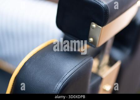 Extreme close up of a black and gold barber chair from the left back side angle, captured in a horizontal format with elegant detail. Stock Photo