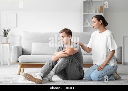 Young woman supporting man with suicidal thoughts at home Stock Photo
