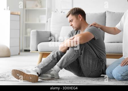 Young woman supporting man with suicidal thoughts at home Stock Photo