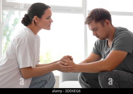 Young woman supporting sad man with suicidal thoughts at home Stock Photo