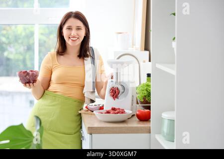 Young housewife using meat grinder in kitchen Stock Photo