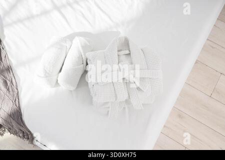 Folded bathrobes with towels on bed in hotel room, top view Stock Photo