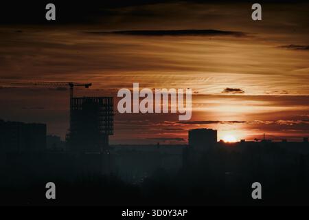 Construction crane sunrise real estate development in city center. Fast moving clouds over modern office building under construction symbolize growth Stock Photo