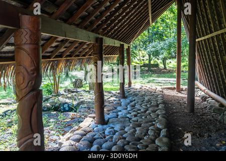 A traditional thatched-roof structure stands amid ancient stone ruins ...