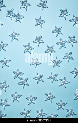 Transparent crystal stars on a light blue background with shadows. Stock Photo