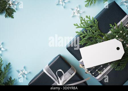 Blue present boxes with empty gift tag on light blue background. Space for your text. Stock Photo