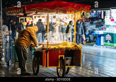 Grilled roasted corn on the cob sold by a street vendor in the illuminated streets of the Sultanahmet district at night in Istanbul, Turkey. Stock Photo