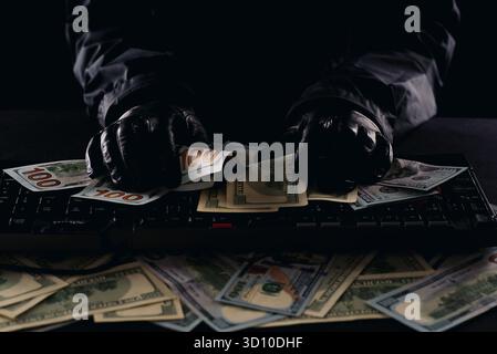 Hacker's hands on a computer keyboard rake in money Stock Photo