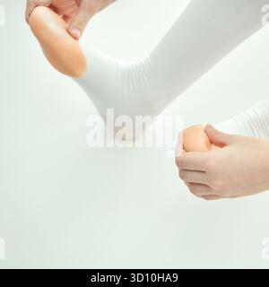 Young caucasian female dancer adjusting pointe shoes for ballet performance on white background. Stock Photo