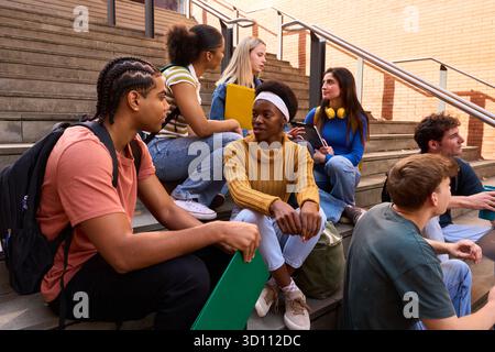Multiethnic group of students sitting talking on campus stairs Stock Photo