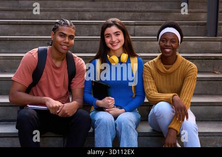 Diverse students sitting on campus stairs smiling Stock Photo