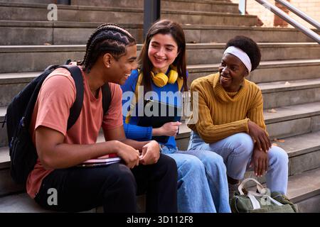 Diverse university students laughing, talking on campus stairs Stock Photo
