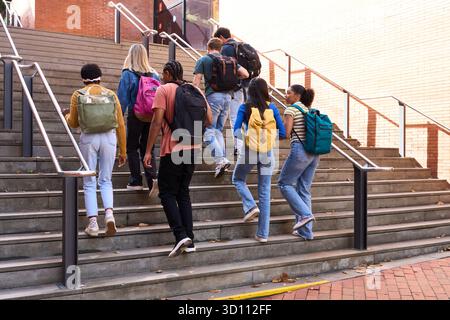 Diverse students walking up school stairs on campus Stock Photo
