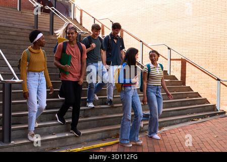 Diverse students walking down university stairs together Stock Photo