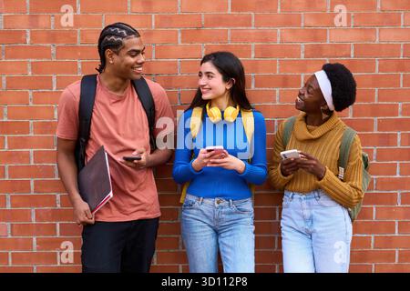 Diverse students using phones, connecting, and smiling Stock Photo