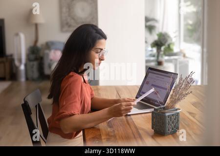 Serious busy young Hispanic business woman analyzing paper document Stock Photo