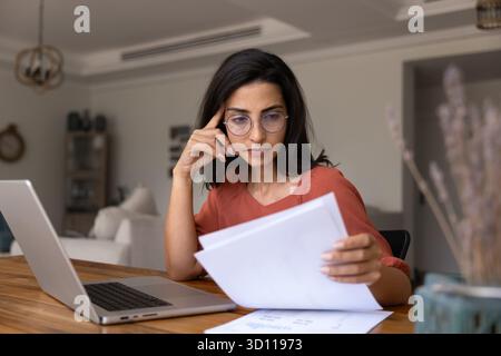 Focused thoughtful young Latin professional woman working on project Stock Photo