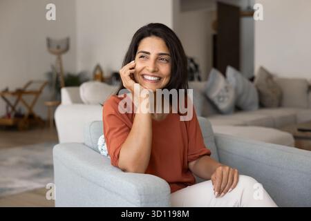 Happy young Hispanic homeowner woman enjoying being at cozy home Stock Photo