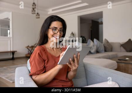 Happy Hispanic gadget user woman using smart application on tablet Stock Photo