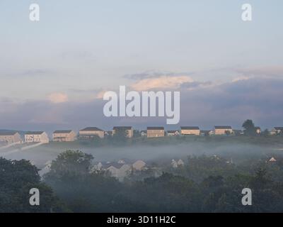 Golden sunlight breaks through morning fog, illuminating a peaceful residential neighborhood in Pennsylvania, USA. Stock Photo