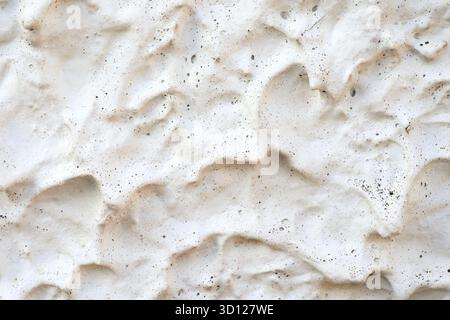 Close-up view of a textured wall showcasing natural patterns. The surface has a soft, uneven design in light colors, highlighting its organic appearan Stock Photo