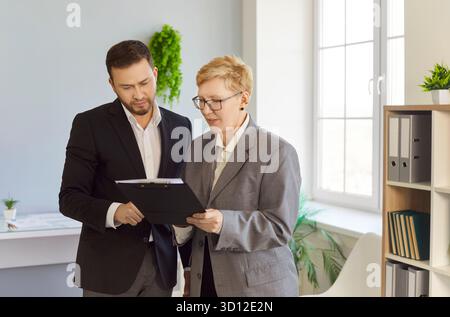 Business colleagues discussing planning and strategy with clipboard in office Stock Photo