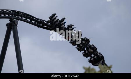 October 2025, Energylandia amusement park, Krakow, Poland. Visitors experience an intense upside-down turn on a roller coaster against a cloudy sky. T Stock Photo