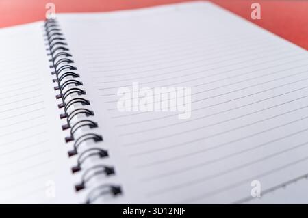 Close-up shot of an open spiral-bound notebook. The clean, white, lined pages are empty, providing copy space. Perfect background for education Stock Photo