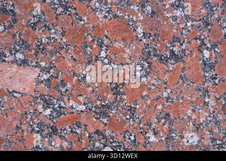 Close up texture of red granite stone with black and white flecks.  Stock Photo