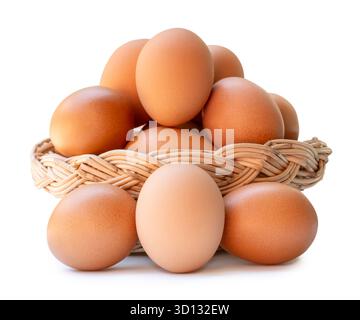 Many brown chicken eggs in stack in wicker basket are isolated on white background with clipping path. Stock Photo