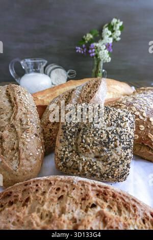 Freshly baked artisanal bread featuring various types and textures, displaying a rich culinary tradition with milk and flour in the background Stock Photo