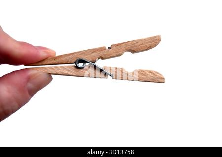 A wooden clothespin in hand isolated. An open clothes peg held in fingers. Stock Photo