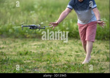 Drone quadcopter with digital camera flying over green grass. A man launches a drone Stock Photo