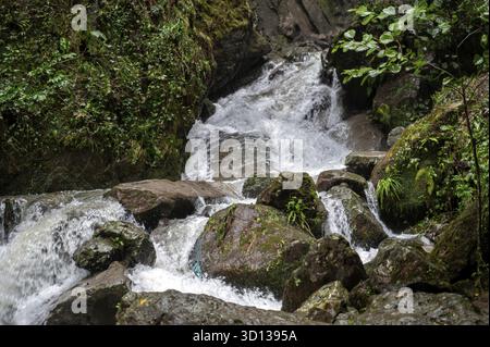 Rapid and powerful water flow between large rocks, close-up. Boulders ...