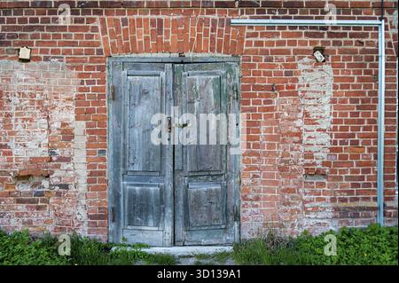 Old wooden door in a red brick wall. Close-up Stock Photo