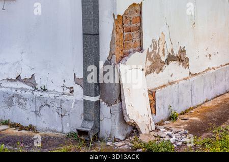 Damaged building exterior with peeling paint and exposed brick, showing neglect, decay, and renovation needs Stock Photo