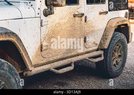 6 September 2025, Perucac, Serbia: Side of an off road SUV covered in mud after adventure driving, showing dirty door, fender, and tire Stock Photo