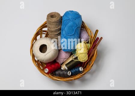 Assortment of yarn spools and threads in a woven basket, displaying a variety of colors and textures, ideal for creative crafting and DIY projects Stock Photo
