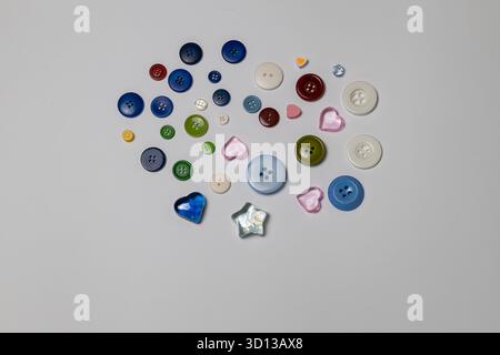 Colorful buttons in various shapes and sizes, including hearts and stars, are arranged artistically on a light background Stock Photo