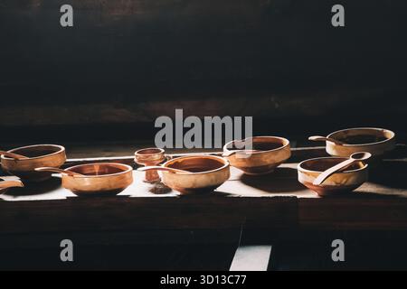 Rustic handcrafted ceramic bowls with wooden spoons arranged on a dark wooden surface, highlighting artisan craftsmanship and traditional style Stock Photo