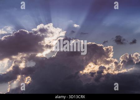 Dark cumulus clouds filling the sky, sunbeams piercing through silver linings, creating a beautiful moody atmosphere Stock Photo