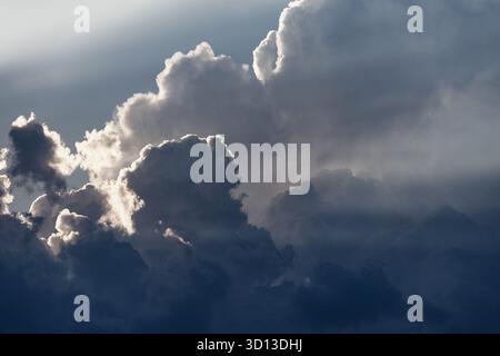 Dark cumulus clouds filling the sky, sunbeams piercing through silver linings, creating a beautiful moody atmosphere Stock Photo