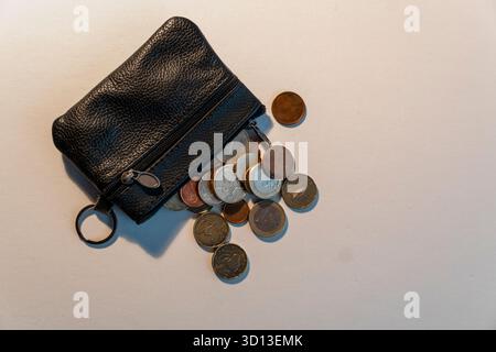 A black purse with coins in it. The purse is full of coins and the coins are of different sizes and colors Stock Photo