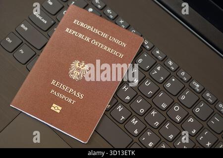 Austria passport lies on black laptop keyboard buttons background close up. Technologies and control in Europe concept Stock Photo