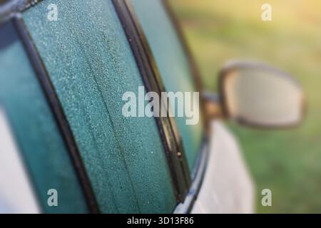 Car window frosting on a cold morning. Ice crystals covering glass, showing winter concept and low temperature Stock Photo