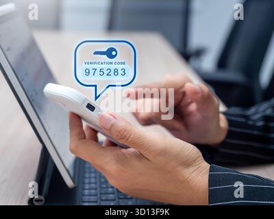 User entering verification code from smartphone for two-factor authentication (2FA), representing OTP security, digital identity protection, login saf Stock Photo