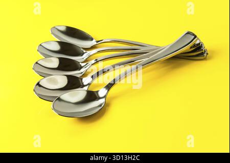 Plastic spoons painted under metal on a yellow background Stock Photo