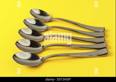 Plastic spoons painted under metal on a yellow background Stock Photo